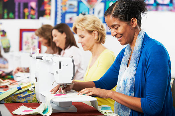 Group Of Women Enjoying Using Electric Sewing Machines In class Together